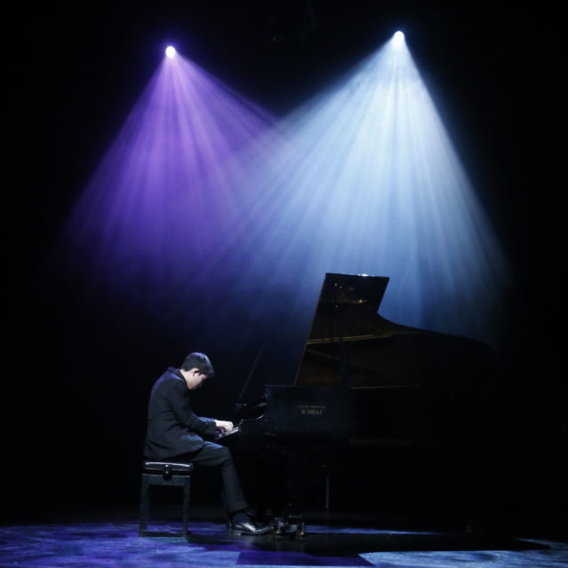 Male student plays piano on stage