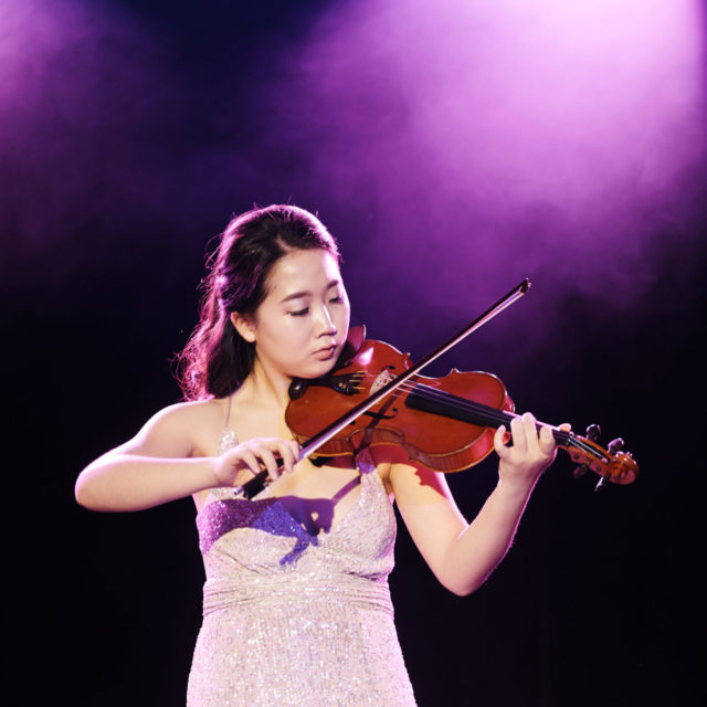 Senior female student in a gown playing violin