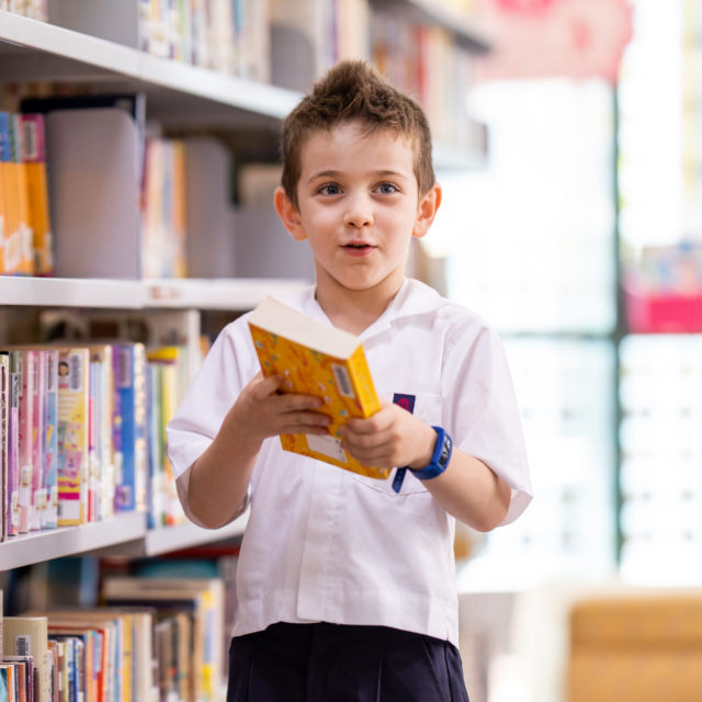 Kindy boy in library with open book
